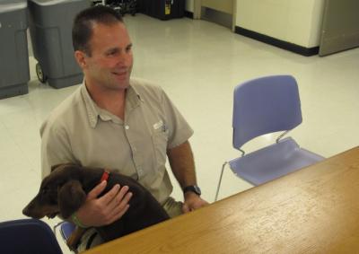 Inmate Scott Abram, holding a training dog, Ziva,  talks about his work counseling fellow inmates including some who are dying and spending their last days in a prison hospice program, on Friday, Sept. 11, 2015 in Columbus, Ohio. Abram, serving 15 years to life for murder, also trains puppies that may end up as pilot dogs.  (AP Photo/Andrew Welsh-Huggins)
