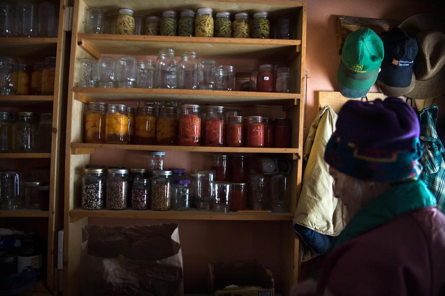 Jane Faller dons a coat in her mudroom containing canned goods on Wednesday. Everywhere she looks, she sees reminders of her late husband. Jane and Bob canned the goods last summer and they remain stored on a shelf he built for them next to a collection of his favorite hats.