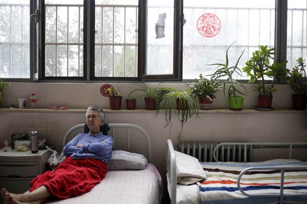 A woman rests in bed at the Songtang Hospice, Beijing, July 19, 2016. The plants by the window were donated by hospice volunteers. 