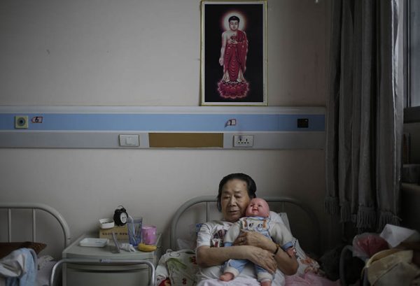 A woman holds a doll donated by a hospice volunteer at Songtang Hospice, Beijing, July 19, 2016.