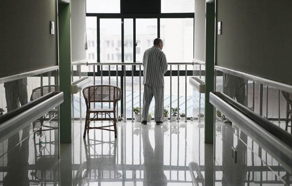 A man stands by a window at the end of the hallway at Putuo District Shiquan Street Community Health Service Center, Shanghai, May 5, 2013.