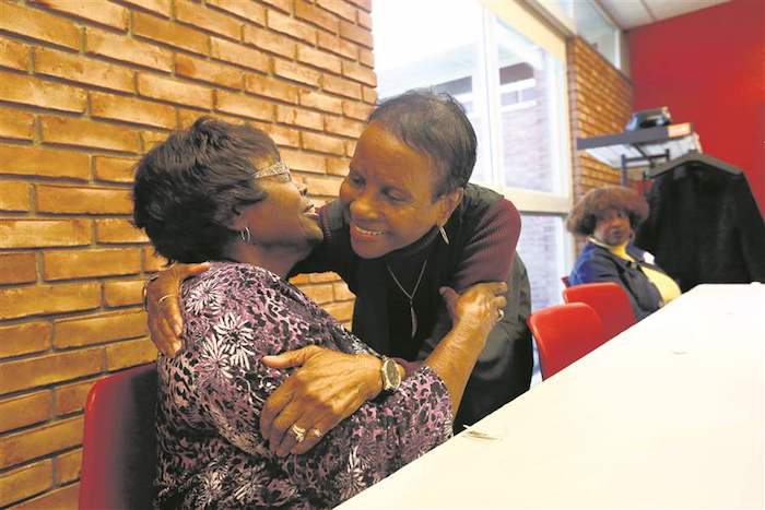 Widows Josephine Cleaves, left, and Aleada Whitehead, right, both of Toledo, hug each other during a support group for widows at Reynolds Corners Library.
